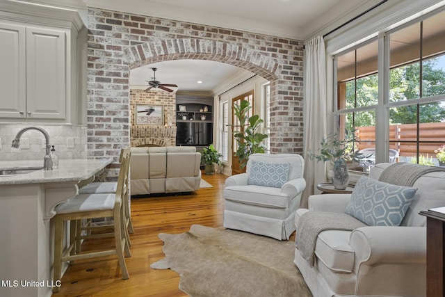 133 Sycamore Rdg, Madison, MS 39110 - living room featuring light wood-type flooring, a ceiling fan, arched walkways, brick wall, and ornamental molding