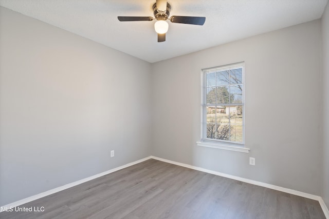 unfurnished room with a textured ceiling, wood finished floors, baseboards, and ceiling fan