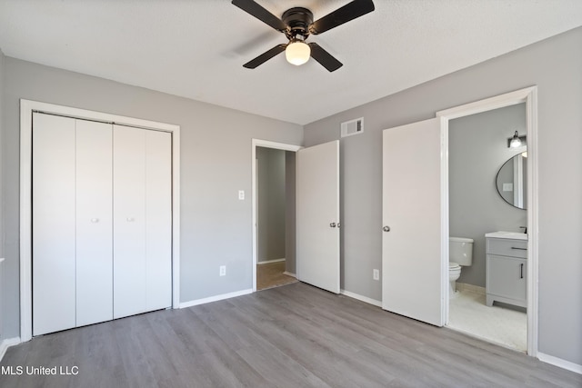 unfurnished bedroom with a closet, baseboards, visible vents, and wood finished floors