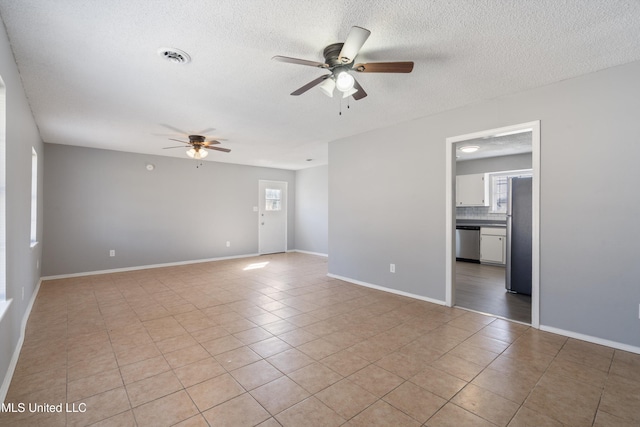 empty room featuring light tile patterned floors, a ceiling fan, visible vents, and baseboards