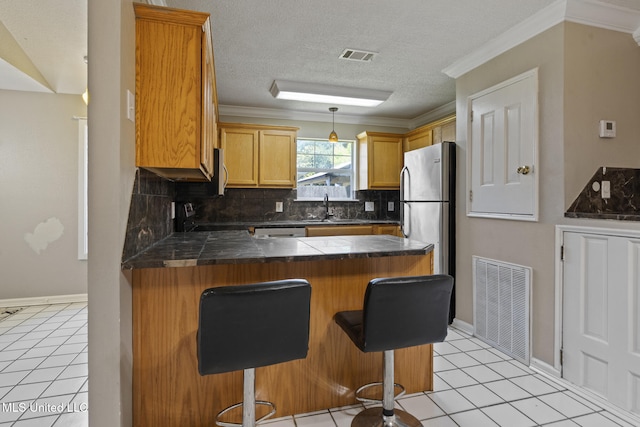 4504 E Magnolia Cv, Diberville, MS 39540 - kitchen with freestanding refrigerator, a peninsula, a sink, decorative backsplash, and light tile patterned floors