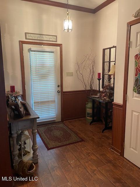 doorway to outside featuring a wainscoted wall, wood-type flooring, and crown molding