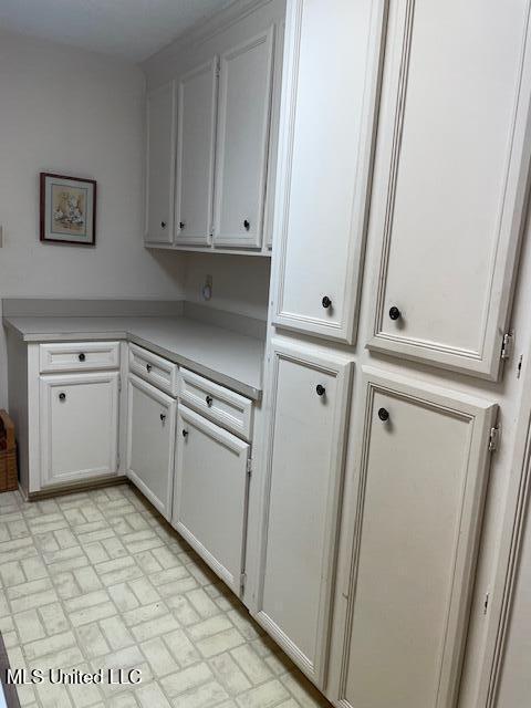 kitchen with white cabinetry, light countertops, and brick patterned floor