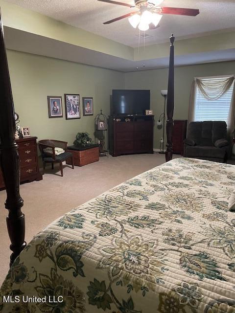 bedroom featuring a textured ceiling, a ceiling fan, and light carpet