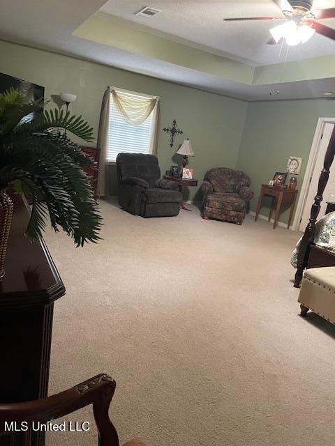 living room with a tray ceiling, carpet floors, and visible vents