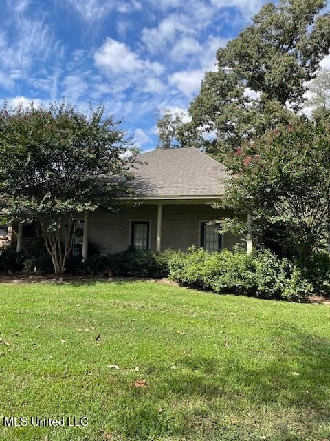 view of front of house featuring a shingled roof and a front lawn