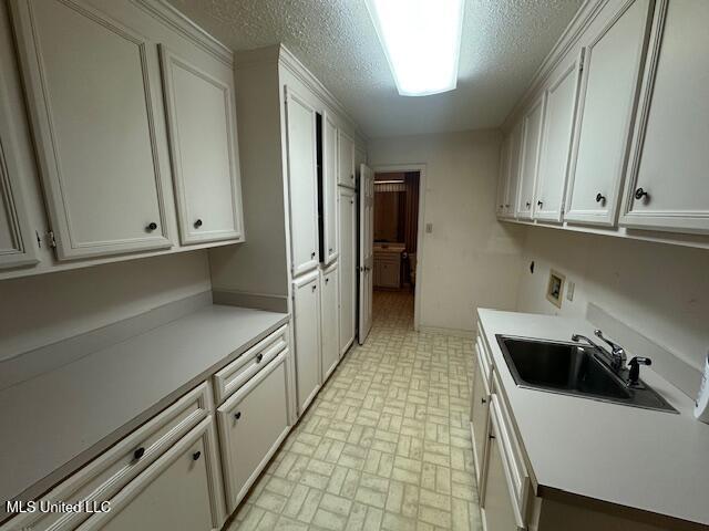 kitchen featuring a sink, light countertops, white cabinets, a textured ceiling, and dishwasher