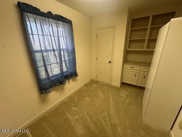 interior space featuring carpet, baseboards, and freestanding refrigerator