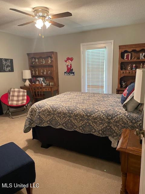 bedroom with a textured ceiling, a ceiling fan, and carpet