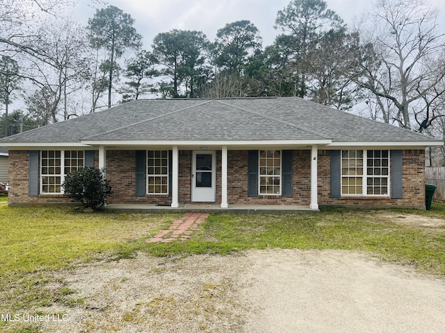 ranch-style house featuring a shingled roof, a front yard, brick siding, and a porch