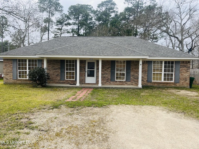 ranch-style house with covered porch, brick siding, a front yard, and a shingled roof