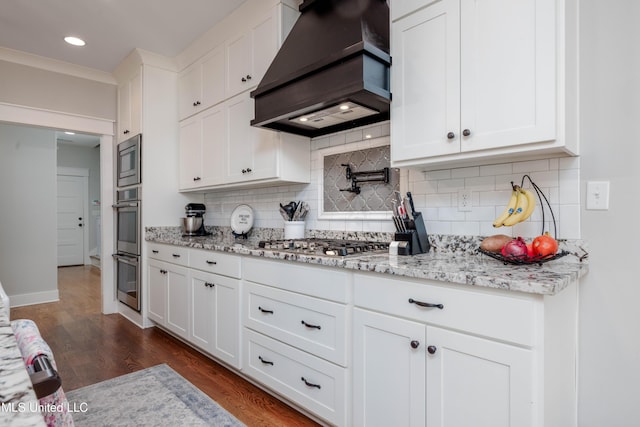 kitchen featuring dark wood-style floors, stainless steel appliances, decorative backsplash, custom range hood, and white cabinets