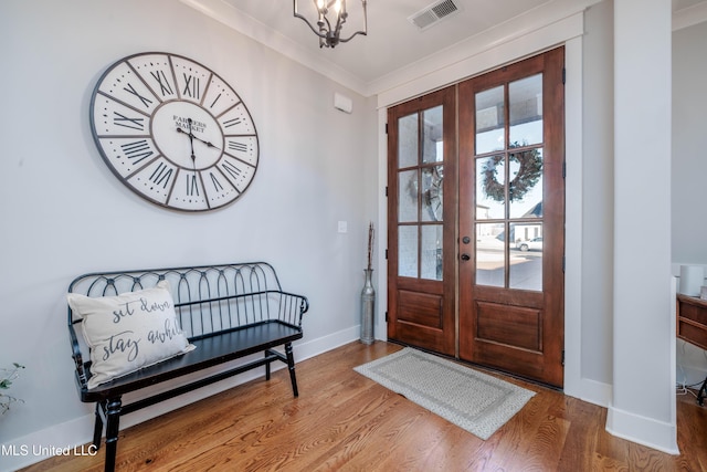 foyer entrance with visible vents, ornamental molding, french doors, an inviting chandelier, and wood finished floors