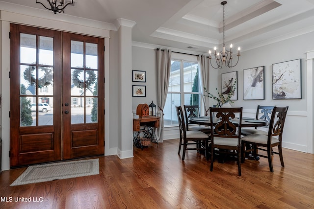 dining area featuring wood finished floors, a tray ceiling, ornamental molding, french doors, and a chandelier