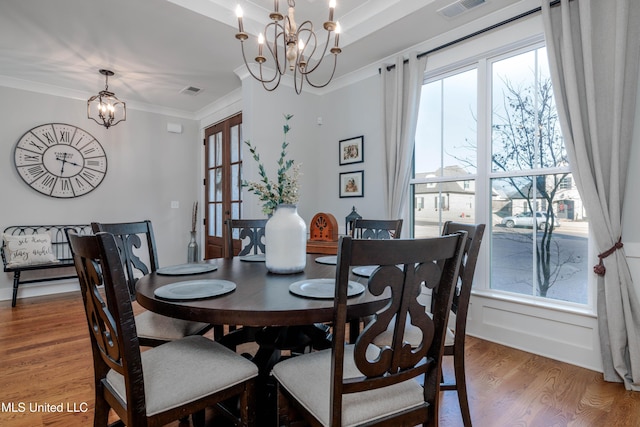 dining room featuring a chandelier, visible vents, light wood-style flooring, and crown molding