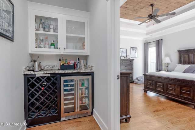 bedroom with wine cooler, light wood-style floors, a raised ceiling, a dry bar, and wooden ceiling