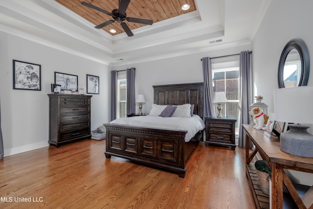 bedroom with a raised ceiling, ornamental molding, visible vents, and light wood-type flooring