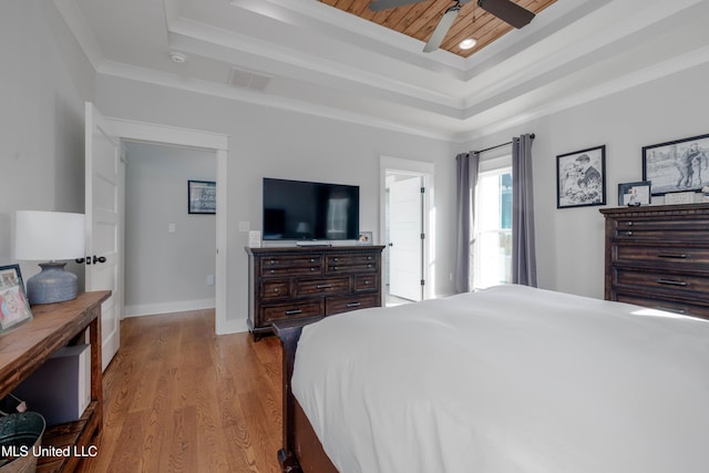 bedroom featuring visible vents, crown molding, baseboards, a tray ceiling, and wood finished floors