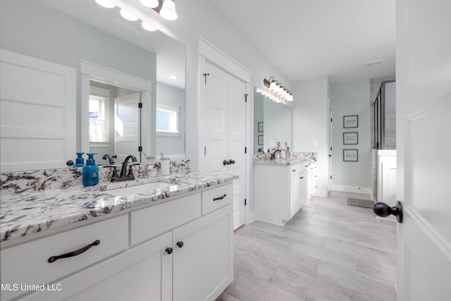 full bath featuring a shower stall, two vanities, and a sink