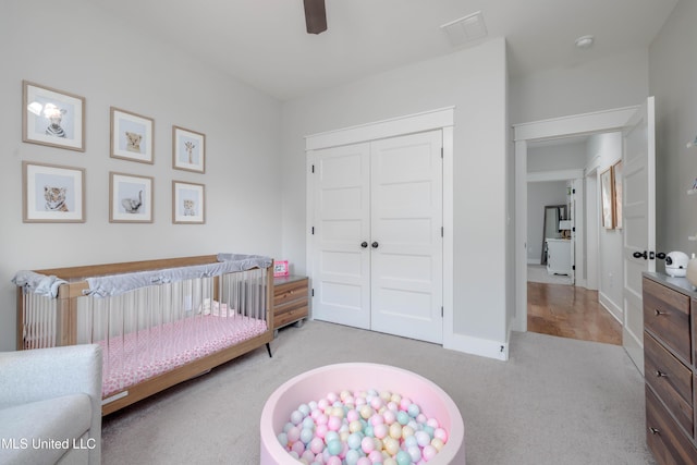 carpeted bedroom featuring visible vents, baseboards, ceiling fan, a nursery area, and a closet