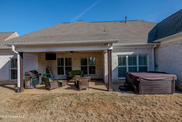 back of property featuring a shingled roof, ceiling fan, a patio area, and a hot tub