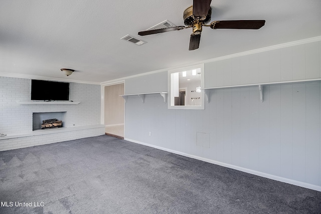 unfurnished living room featuring ceiling fan, dark carpet, ornamental molding, and a brick fireplace