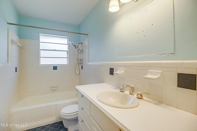 full bathroom with vanity, tile patterned floors, tiled shower / bath combo, toilet, and tile walls