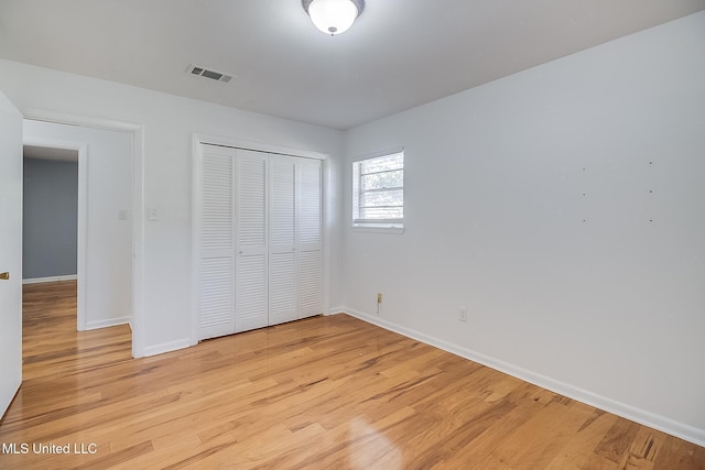 unfurnished bedroom with light wood-type flooring and a closet