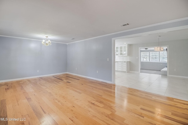 empty room featuring a chandelier, light hardwood / wood-style floors, and ornamental molding