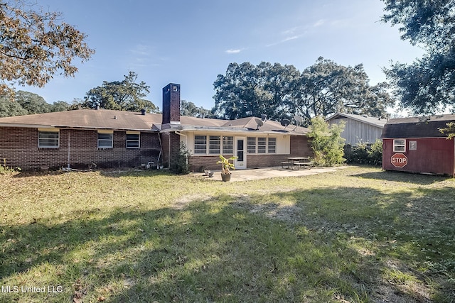 rear view of property featuring a yard, a patio, and a storage shed