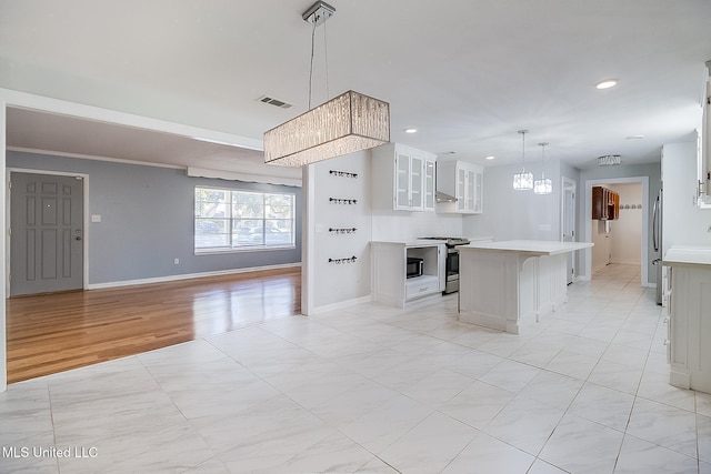 kitchen featuring hanging light fixtures, a kitchen island, stainless steel range oven, a kitchen bar, and white cabinets