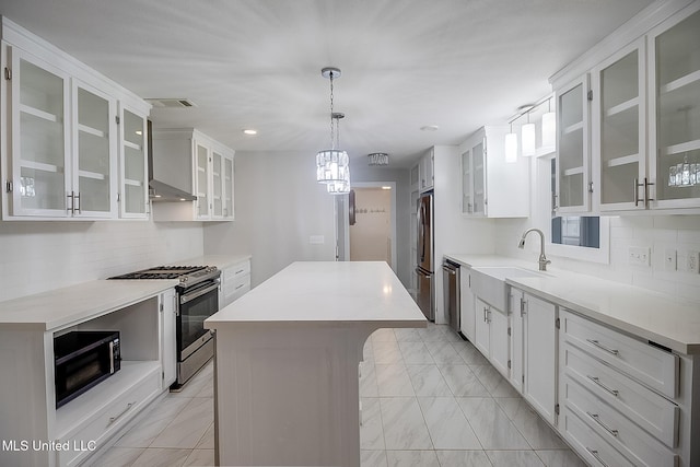 kitchen featuring white cabinets, decorative light fixtures, a kitchen island, and stainless steel appliances