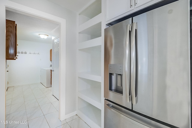 kitchen featuring stainless steel fridge with ice dispenser, light tile patterned floors, and washer and dryer