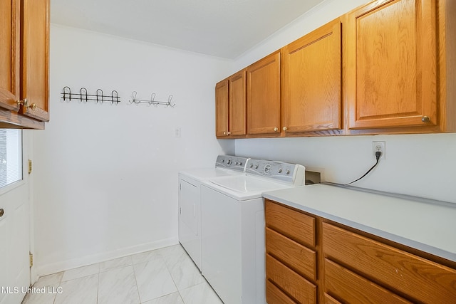 clothes washing area with washing machine and dryer, cabinets, and ornamental molding