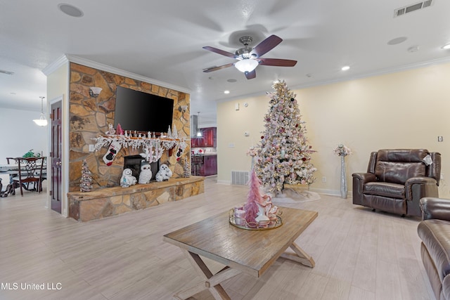 living room with a fireplace, light wood-type flooring, ceiling fan, and ornamental molding