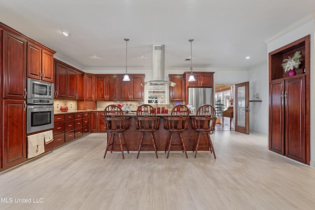 kitchen with decorative backsplash, appliances with stainless steel finishes, exhaust hood, hanging light fixtures, and an island with sink