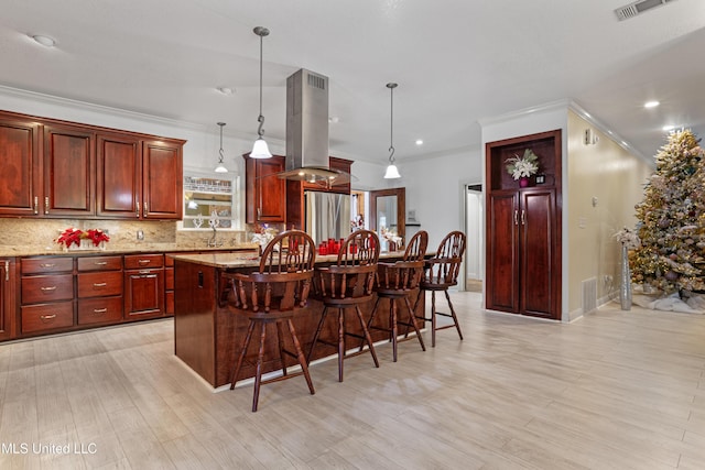 kitchen with stainless steel fridge, island range hood, a center island, hanging light fixtures, and a breakfast bar area