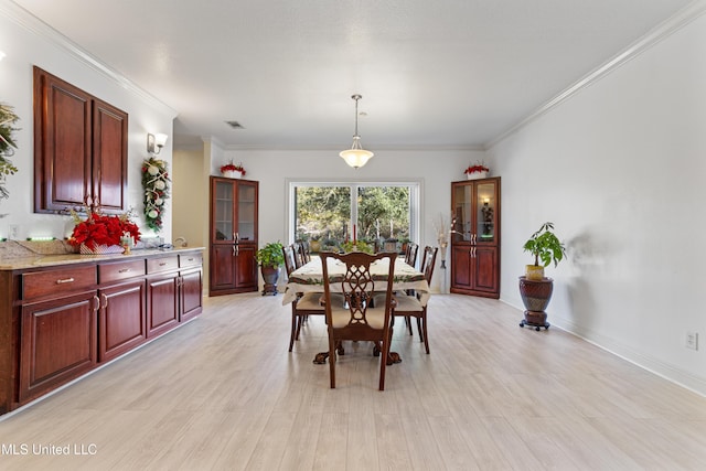 dining space with light hardwood / wood-style flooring and crown molding