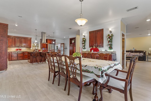 dining area featuring light wood-type flooring and crown molding