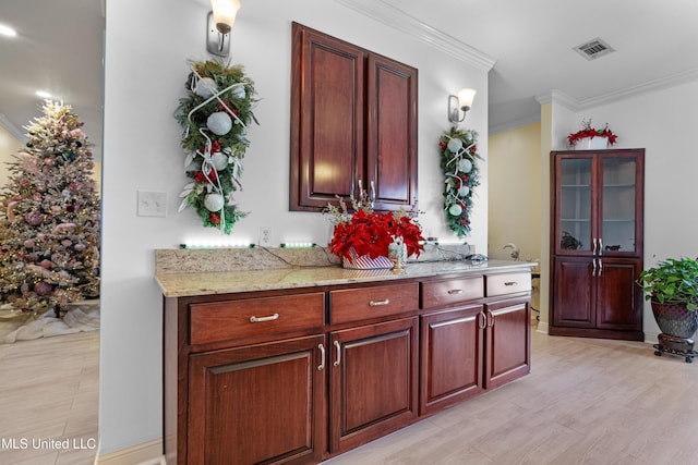 interior space featuring light stone countertops, light hardwood / wood-style flooring, and ornamental molding