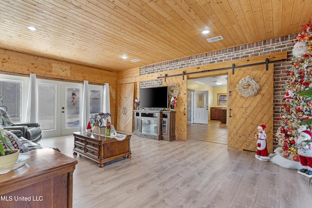 living room with a barn door, brick wall, wooden walls, wood ceiling, and light wood-type flooring