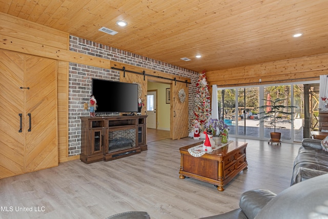 living room featuring a barn door, light wood-type flooring, brick wall, and wooden ceiling