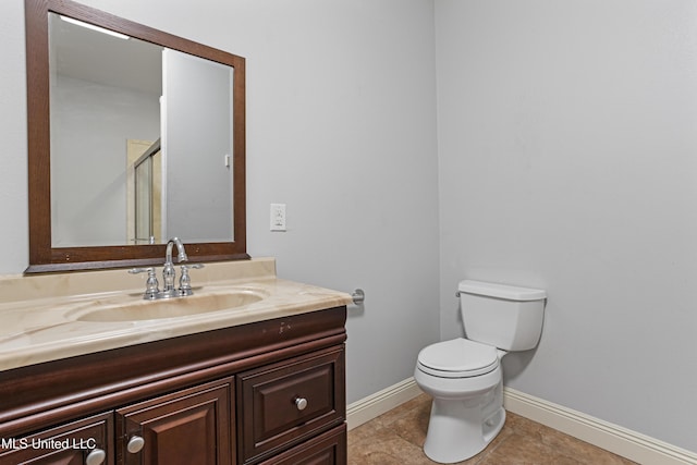 bathroom featuring tile patterned flooring, vanity, toilet, and an enclosed shower