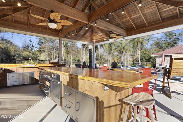 view of patio / terrace featuring a gazebo, an outdoor kitchen, ceiling fan, and sink