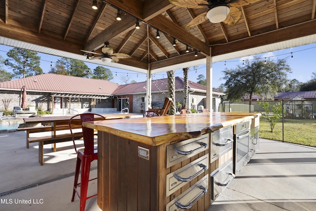 view of patio / terrace with a gazebo, ceiling fan, and a bar