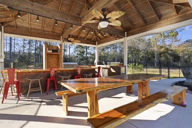 sunroom / solarium featuring vaulted ceiling with beams, track lighting, ceiling fan, and wooden ceiling