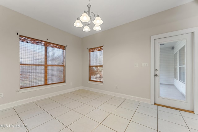 tiled spare room with a healthy amount of sunlight and a notable chandelier