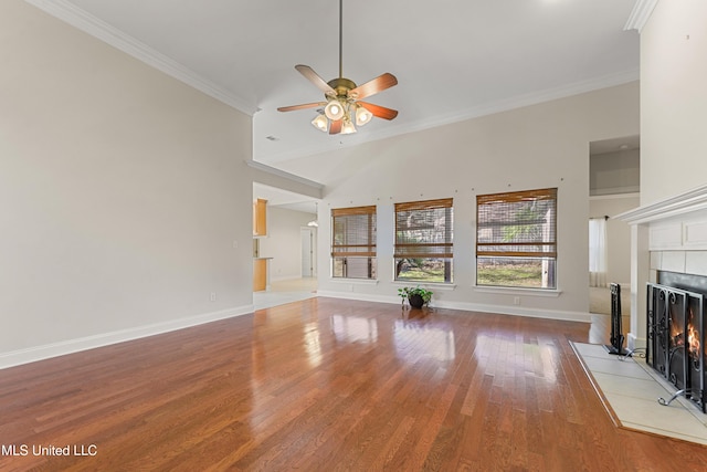 unfurnished living room featuring ceiling fan, a tile fireplace, wood-type flooring, ornamental molding, and high vaulted ceiling