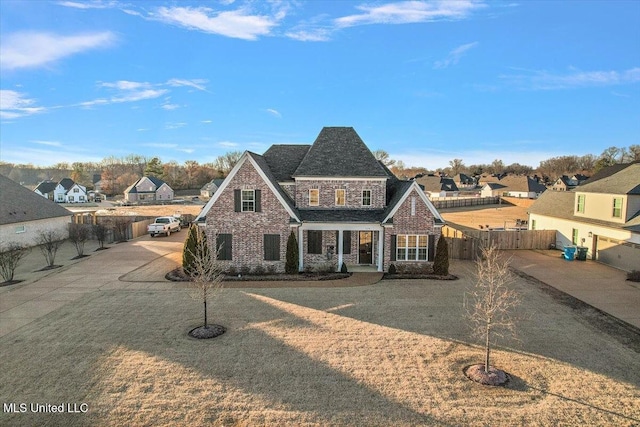 view of front of house with a residential view, brick siding, and fence