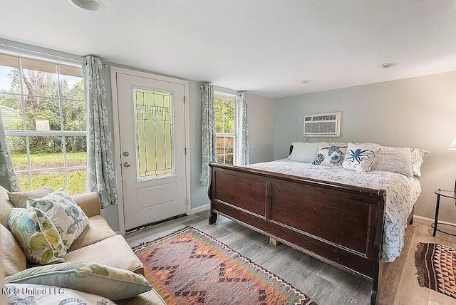 bedroom with light hardwood / wood-style flooring and a wall mounted air conditioner